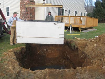 Photo of concrete septic tank being lowered into ground by Statewide Environmental Services technicians as part of overall septic services the company offers.