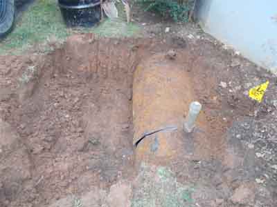 Photo of an underground oil tank with a white pipe protruding from top being prepared for removal by Statewide Environmental Services.