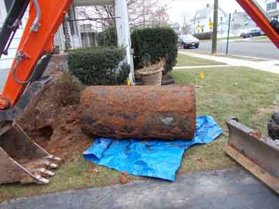 Photo of old, rusty oil tank lying on blue tarp to protect the lawn; Statewide Environmental Services takes precautions to preserve property while performing oil tank removal services.
