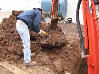 Photo of Statewide Environmental Services technician using a probe to test soil from the excavation of an underground oil tank.