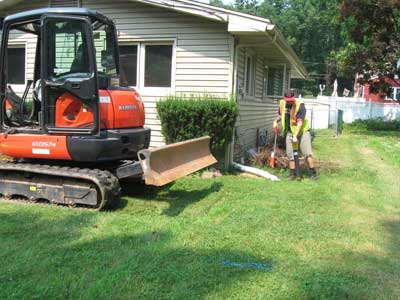 Photo of orange all-terrain truck with plow blade in front of ranch-style home with technician sweeping to locate buried underground oil tank