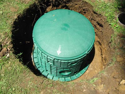 Photo on plastic tank lid in lawn of residential property; Statewide Environmental's septic parts replacement services includes tank lids and risers